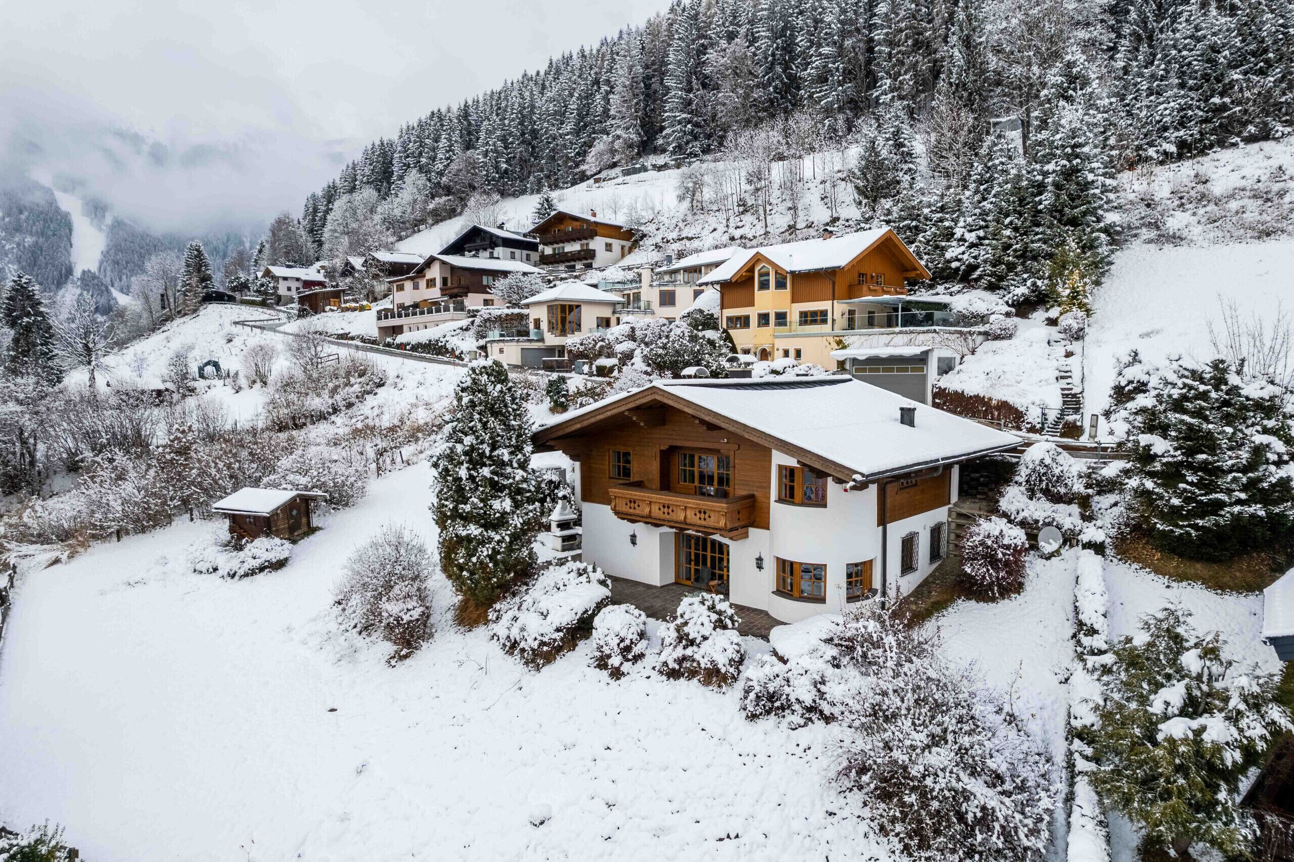 A snow-covered mountain resort with multiple chalet-style buildings, each featuring balconies and large windows.