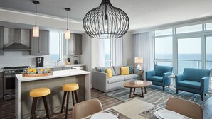 A modern hotel room with a kitchen, dining area, and seating space with a view.