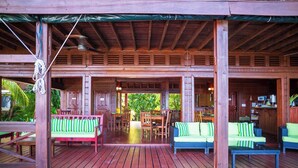 Eine Holzterrasse mit Sitzgelegenheiten im Freien, darunter eine Couch und Stühle, sowie ein Essbereich mit Tischen und Stühlen.