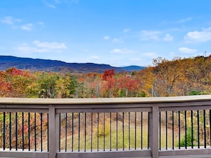 A view from a balcony with a railing, overlooking a landscape with autumn-colored trees and distant mountains. - On Eagle's Wings by Jackson Mountain Rentals (Gatlinburg)