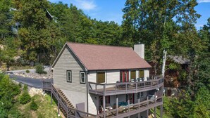A two-story house with a balcony, surrounded by trees and a road. - On Eagle's Wings by Jackson Mountain Rentals (Gatlinburg)