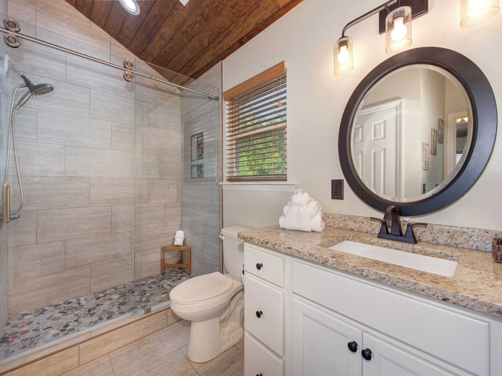 Une salle de bain moderne avec une douche à parois de verre, des toilettes et un meuble-lavabo avec un évier et un miroir.
