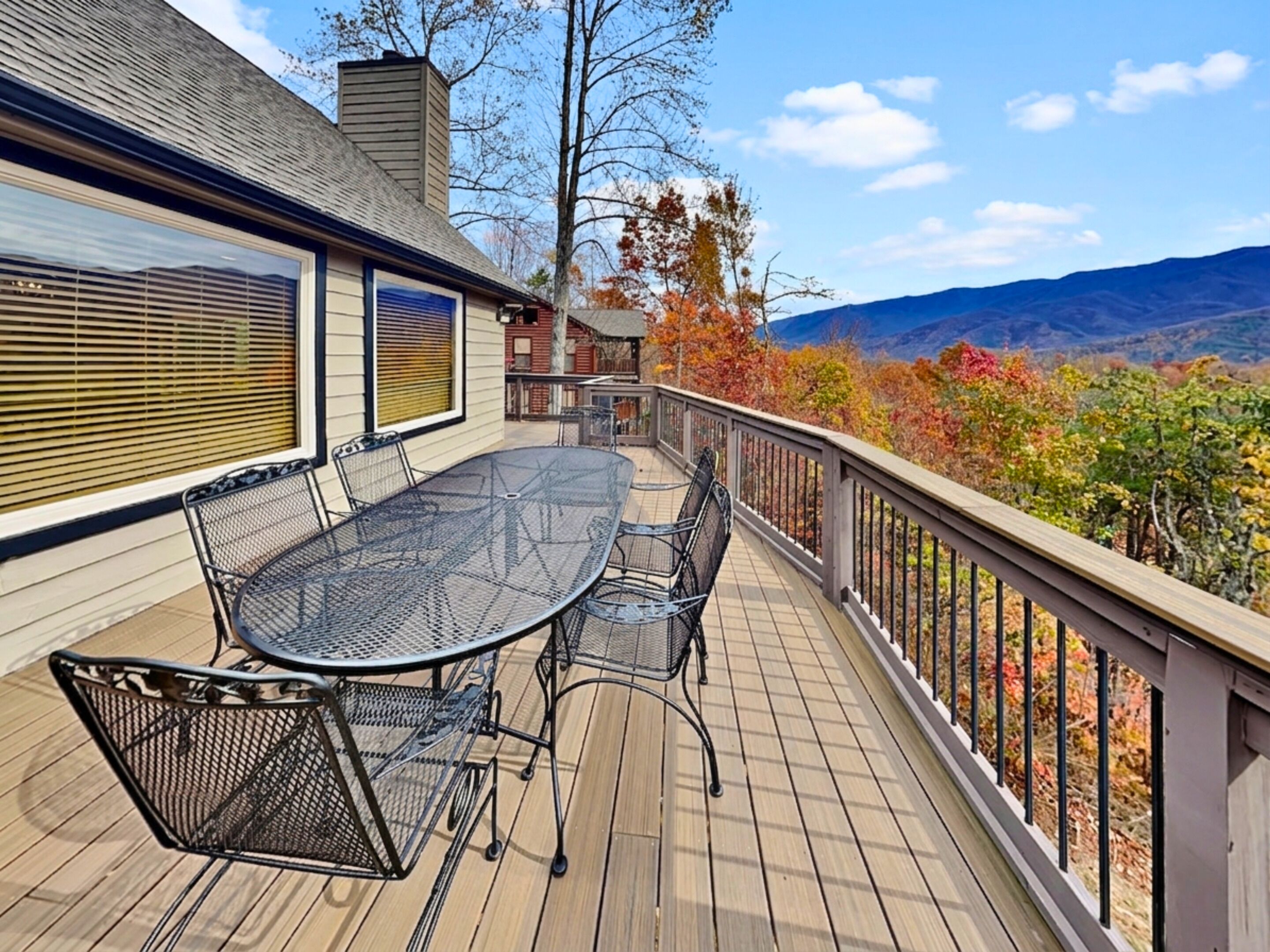 Une terrasse dotée d’une table et de chaises, offrant une vue panoramique sur un paysage de forêts et de montagnes.
