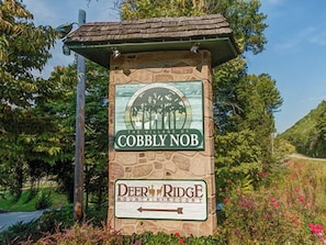 A stone sign with 'Cobbly Nob' and 'Deer Ridge Resort' logos, surrounded by greenery.