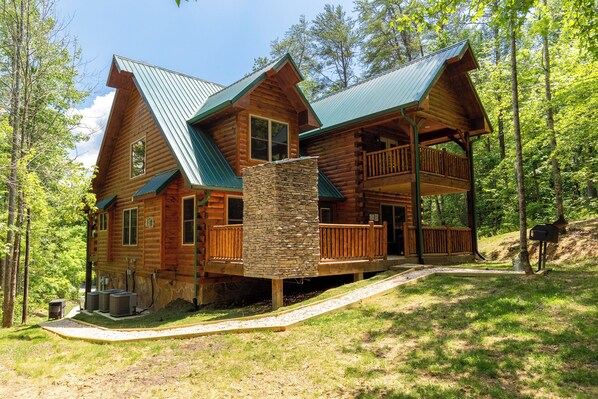 A log cabin with a stone chimney, wooden deck, and a porch with railings. - Fire in the Sky by Smoky Cove Resort (Sevierville)