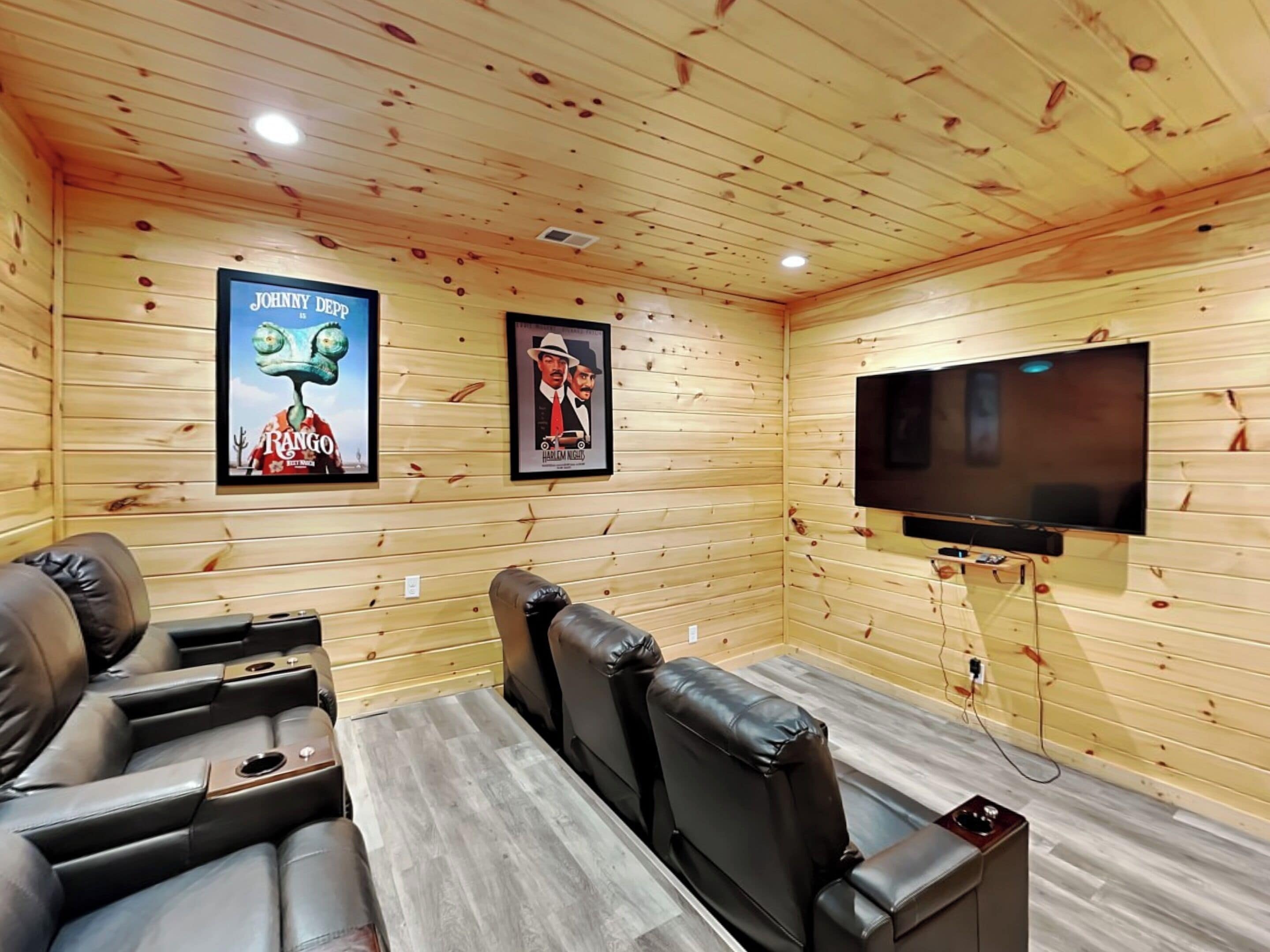 A cozy room with wooden walls, a flat-screen TV mounted on the wall, and leather seating.