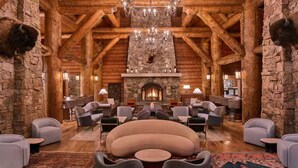 A log cabin interior with a fireplace, wooden beams, and a chandelier. - Ritz-Carlton Bachelor Gulch King Suite. Unmatched Luxury (Edwards)