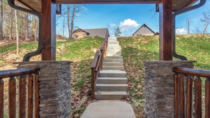 A wooden staircase leading to a covered area with stone walls and wooden railings. - Twisted Pines by Smoky Cove Resort (Sevierville)