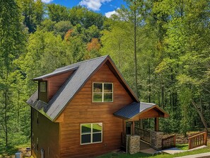 A wooden cabin with a sloped roof, a porch, and a stone staircase leading to the entrance. - Twisted Pines by Smoky Cove Resort (Sevierville)