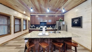 A modern kitchen with wooden cabinets, a granite countertop, and a stainless steel refrigerator. - Twisted Pines by Smoky Cove Resort (Sevierville)