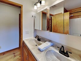 A bathroom with two sinks, wooden cabinets, a large mirror, and a towel on the counter.