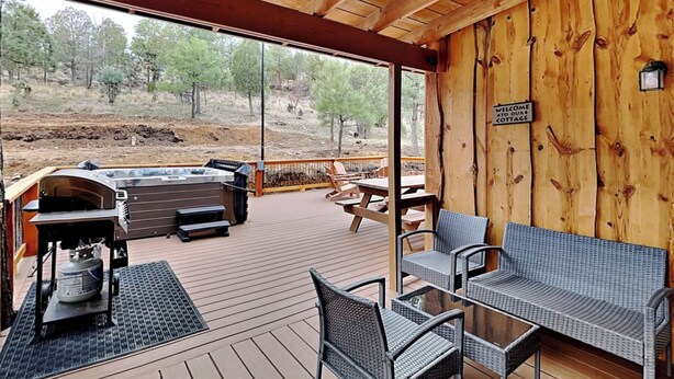 An outdoor deck with a barbecue area, seating, and a view of the surrounding landscape. - Moose Manor by Ruidoso Vacation Rentals (Ruidoso)