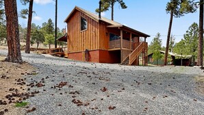 A wooden cabin with a balcony, surrounded by trees. - Moose Manor by Ruidoso Vacation Rentals (Ruidoso)
