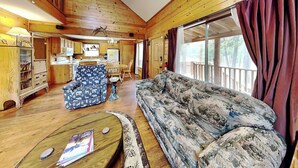 A wooden cabin interior with a sofa, chairs, a dining table, and a kitchen area. - Moose Manor by Ruidoso Vacation Rentals (Ruidoso)