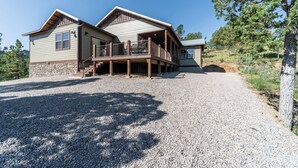 A two-story house with a stone foundation, a covered porch, and a gravel driveway.