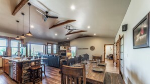 A spacious kitchen with a central island, wooden beams, and pendant lighting.