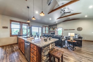 A spacious kitchen with a large island, wooden cabinets, and pendant lighting.