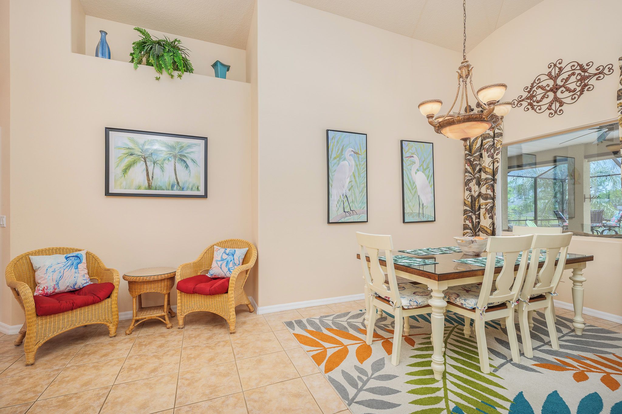 A dining area with wicker chairs, a wooden table, and a chandelier.