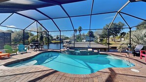 A covered swimming pool with a view of a lake and houses in the background. - Splashing Dolphins by Distinctive Beach Rentals (Palm Coast)