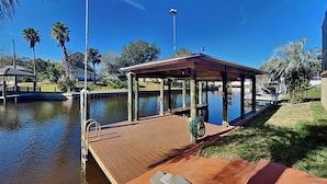 A wooden dock extending into a calm body of water, with a covered seating area and a street lamp nearby. - Splashing Dolphins by Distinctive Beach Rentals (Palm Coast)