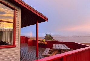 A wooden deck with a red railing, a bench, and a table.
