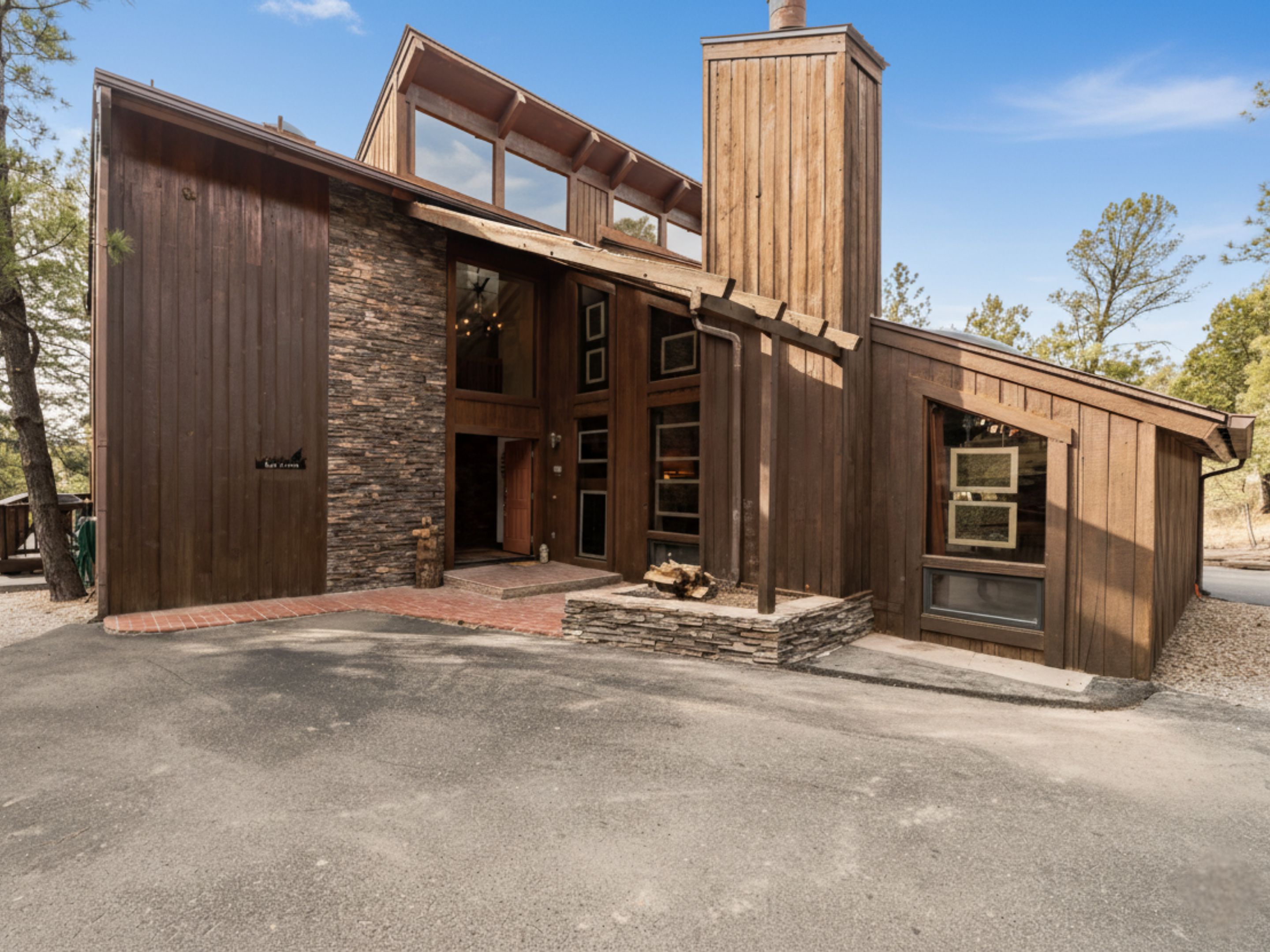 A modern house with a stone facade, large windows, and a prominent chimney.