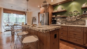 A modern kitchen with a granite countertop, stainless steel appliances, and a dining area with metal chairs. - High Loop by Ruidoso Vacation Rentals (Ruidoso)
