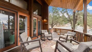 A wooden deck with wicker furniture and a view of trees.