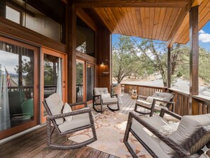 A wooden deck with wicker furniture and a view of trees.