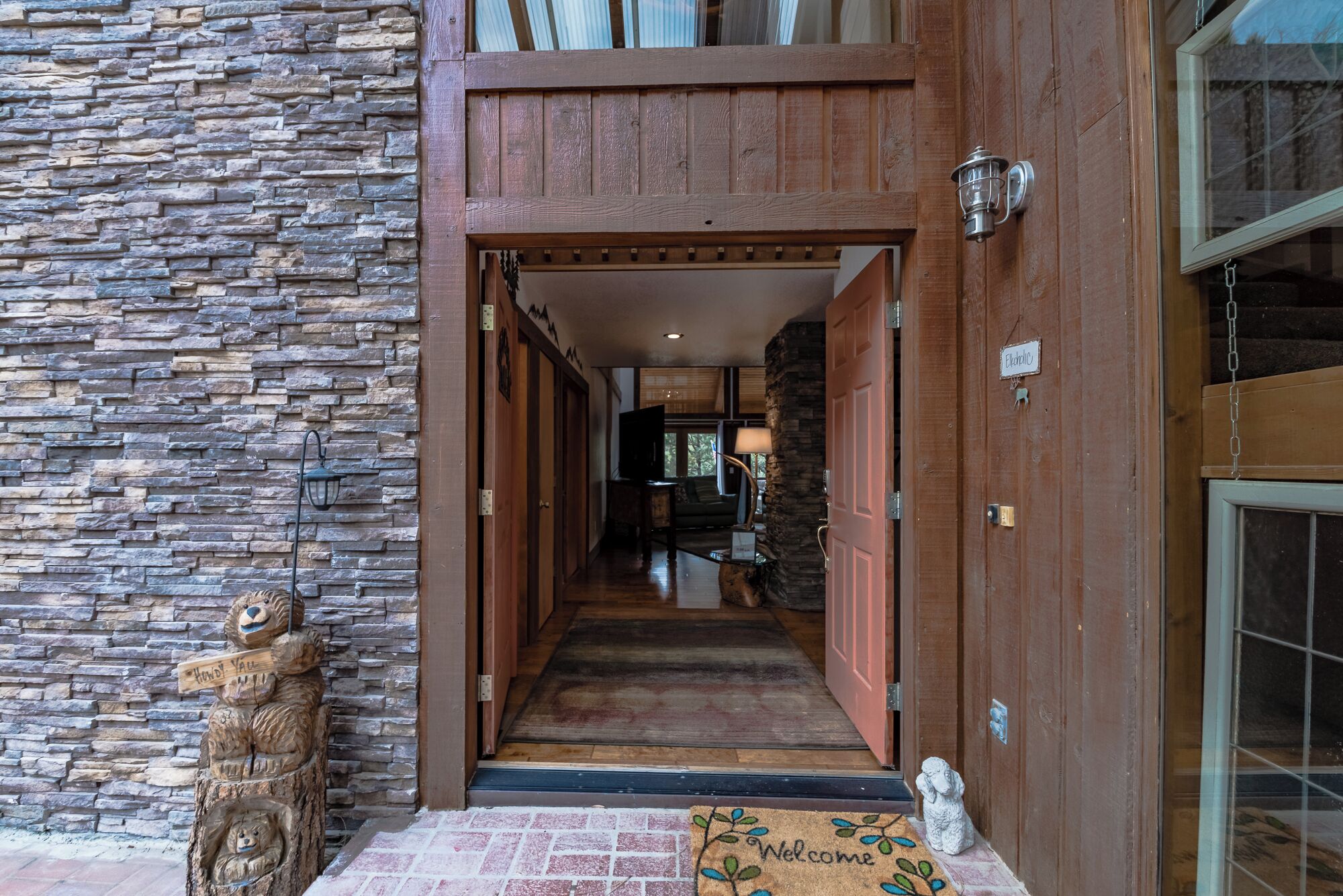 A stone wall, wooden door, and a welcome mat at the entrance of a building.