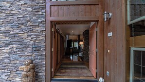 A stone wall, wooden door, and a welcome mat at the entrance of a building. - High Loop by Ruidoso Vacation Rentals (Ruidoso)