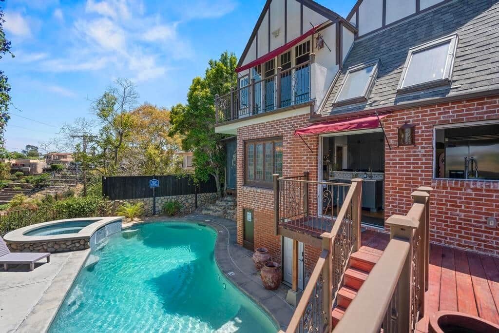 A two-story house with a swimming pool, a deck, and a fenced backyard.