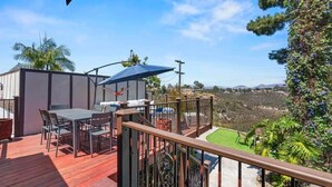 A deck with outdoor furniture, a view of the landscape, and a fenced area. - The Kensington Canyon Estate | Celebrity Vacation Homes (San Diego)