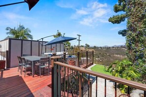A deck with outdoor furniture, a view of the landscape, and a fenced area.