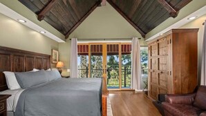 A bedroom with a large bed, wooden headboard, a dresser, and a balcony with glass doors. - The Kensington Canyon Estate | Celebrity Vacation Homes (San Diego)