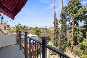 Un balcón con vistas a una zona residencial, con árboles y un edificio distante.