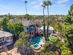 A residential property with a swimming pool, multiple buildings, and surrounding greenery.
