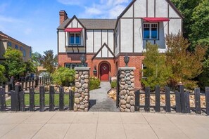 Una casa de dos pisos con un portón de piedra, una puerta roja y fachada de ladrillo.