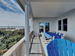A balcony with a view of the ocean, a table with chairs, and a window. - Jean's Dream (St. Augustine)