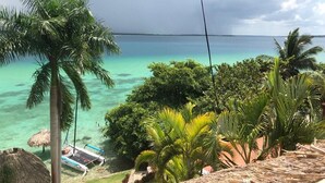 Een tropisch strand met helder turquoise water, palmbomen en een constructie met rieten dak.