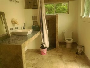 Ein Badezimmer mit weißem Waschbecken, Toilette und Duschbereich.