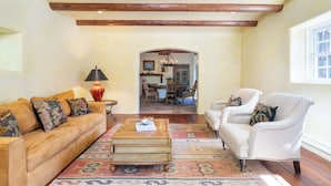 A spacious living room with a wooden ceiling, a sofa, a chair, and a coffee table. - Casita Contenta by Kokopelli Property Management (Santa Fe)