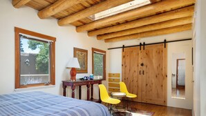Ein Schlafzimmer mit einem Bett, einem Schreibtisch, zwei Stühlen, einem Kleiderschrank und einem großen Fenster.