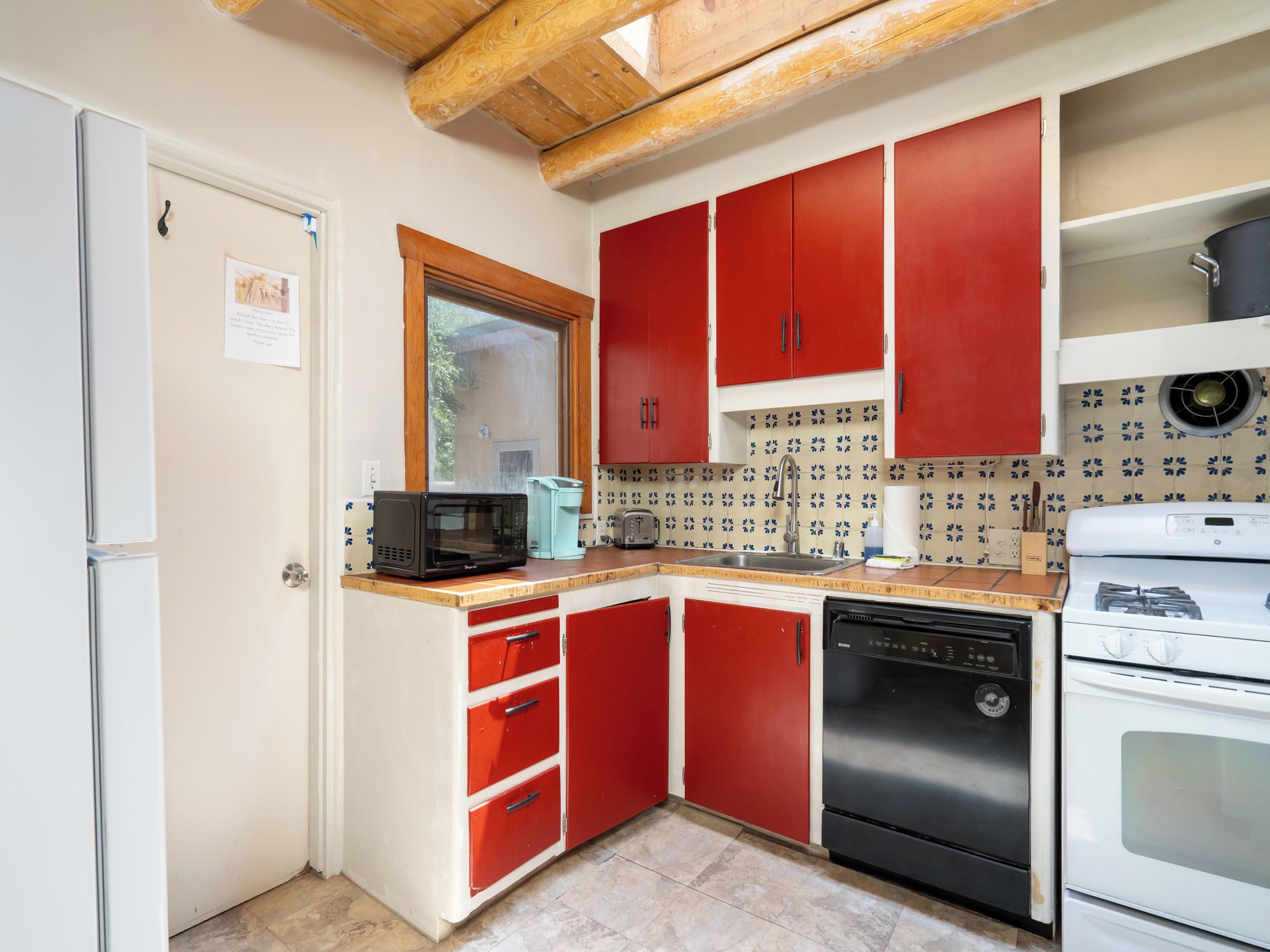 Una cocina compacta con armarios rojos, un microondas, un lavavajillas y una estufa.