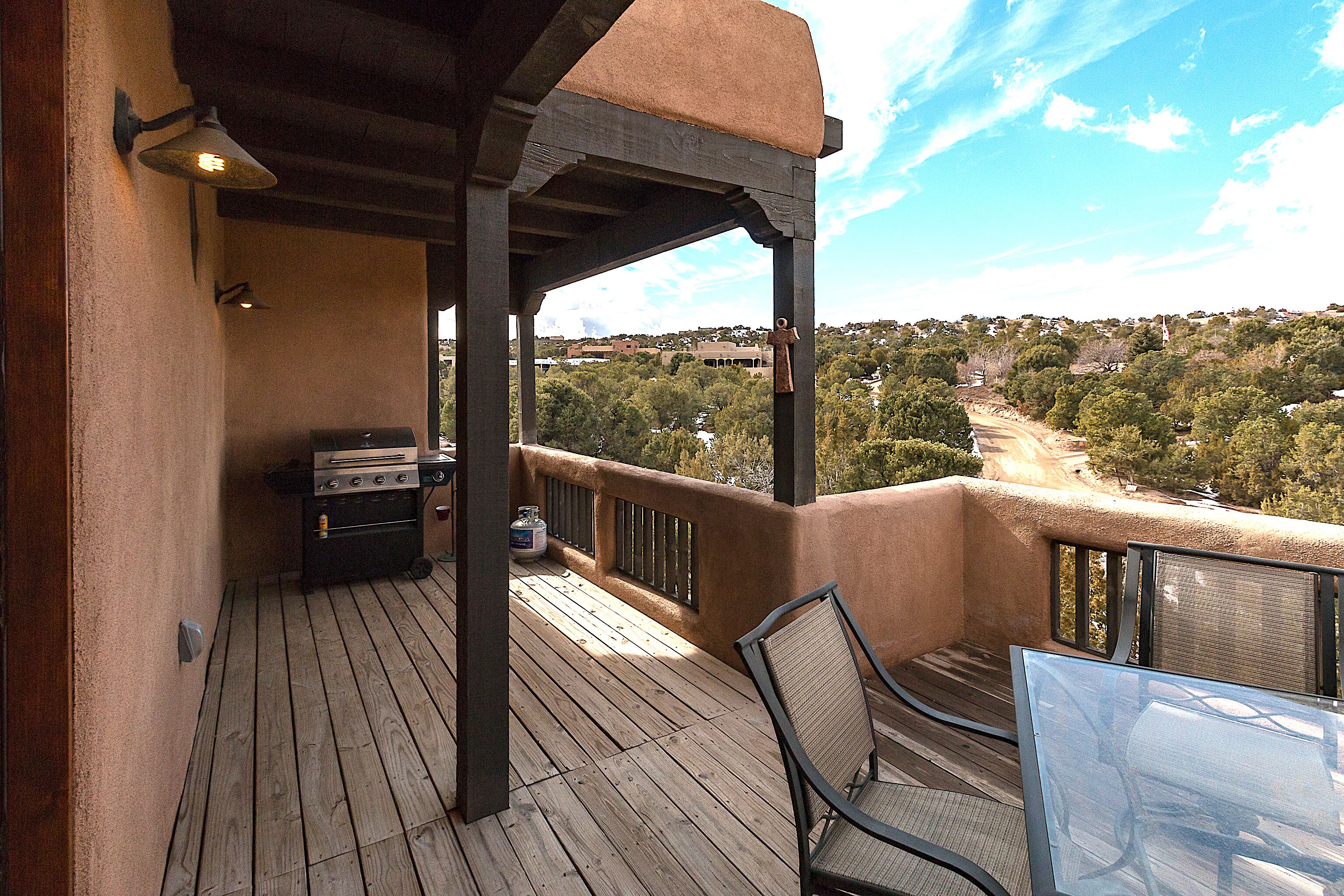 Une terrasse en bois équipée d’un barbecue, de chaises et d’une table, offrant une vue sur un paysage magnifique.