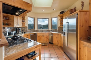 A modern kitchen with wooden cabinets, a stainless steel refrigerator, and a gas stove.