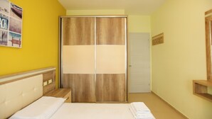 A bedroom with a bed, a wooden wardrobe, a small bedside table, and a wall-mounted shelf. - Holiday One Bedroom Sea View Apartment Vlore (Vlore)