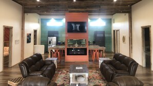 A spacious living room with a fireplace, leather sofas, a coffee table, and a TV mounted on a red wall. - Time For Livin…just a few steps from the Caddo River (Glenwood)