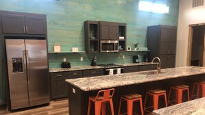 A modern kitchen with a central island, bar stools, stainless steel appliances, and a teal backsplash. - Time For Livin…just a few steps from the Caddo River (Glenwood)