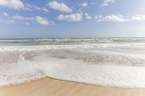 Enjoy the serene beach atmosphere with ocean waves gently approaching the shore.